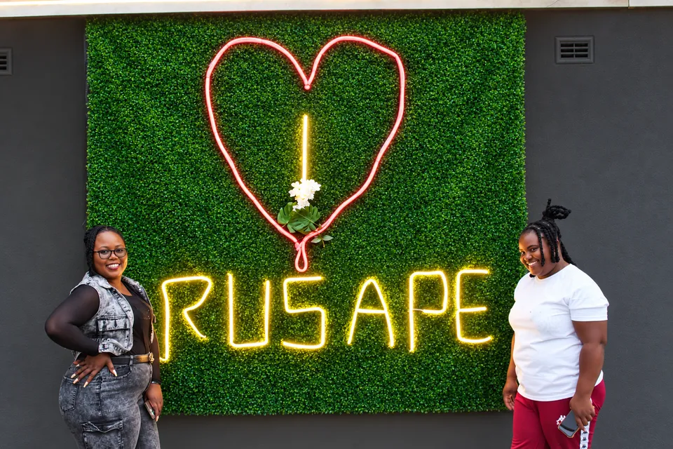 Friends beside the illuminated Rusape heart sign