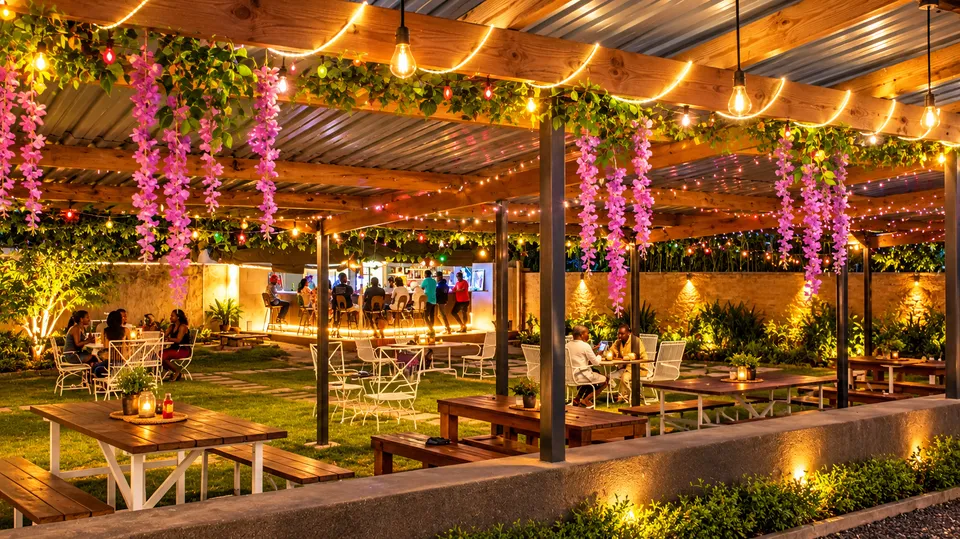 An inviting garden dining space with warm lights and hanging flowers